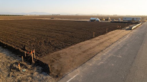 Clean deep-ripped engineered subgrade soil pad completely cleared of almond trees and roots