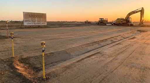 Completed laser-graded dual-slope commercial earthwork surface with Topcon 3D grade stakes